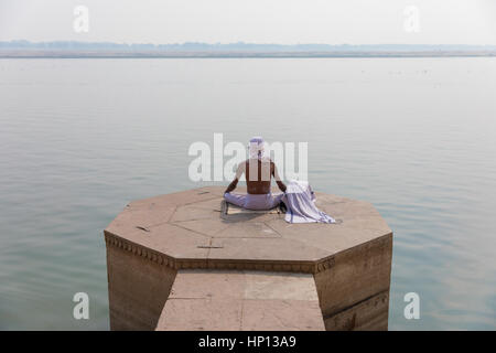 A man meditates on the Ganges River in Varanasi, one of India's holiest cities. Varanasi is a popular destination for tourists attending yoga schools. Stock Photo