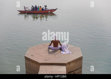 A man meditates on the Ganges River in Varanasi, one of India's holiest cities. Varanasi is a popular destination for tourists attending yoga schools. Stock Photo