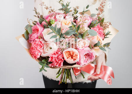 Collection of different varieties of garden roses, carnations and eucalyptus. Girl's hands holding gentle colors flowers bouquet on white background. Stock Photo