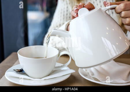Woman pouring a Cup of hot steaming tea in the restaurant. Winter leisure, cold weather, hot drink, love leisure time Stock Photo