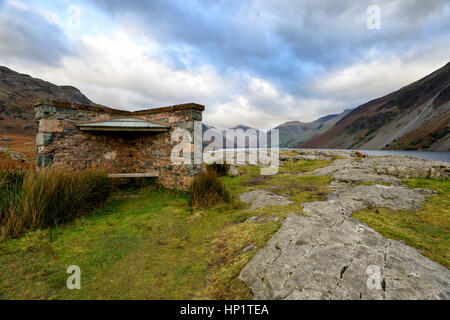 A stone shelter at Wastwater the deepest lake in the Lake District with Scaffell Pike in the distance Stock Photo