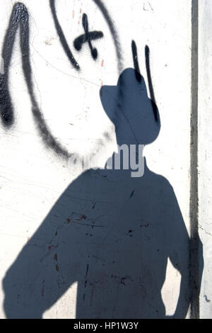 Mann mit Hut als Schatten an einer Mauer - man with hat a shadow on a wall Stock Photo