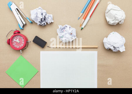 Business concept:Calculator,stapler,red clock,white blank paper,crumpled paper,post it and color pencil,pencil,pen on brown paper background Stock Photo