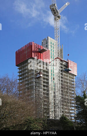 Climbing, protective screens surround the top of a new, concrete framed tower block under construction in Salford Quays, Manchester, UK Stock Photo