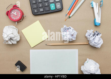 Business concept:Calculator,stapler,red clock,white blank paper,crumpled paper,post it and color pencil,pencil,pen on brown paper background Stock Photo
