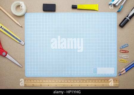 Business concept:stapler,glue,scissor,cutter,tape,pen,pencil,clip,ruler,rubber, cutting mat and color pencil on brown paper background.Top view Stock Photo