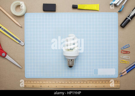 concept:stapler,glue,scissor,cutter,tape,pen,pencil,clip,ruler,rubber, cutting mat ,lamp,crumpled paper and color pencil on brown paper background.Top Stock Photo