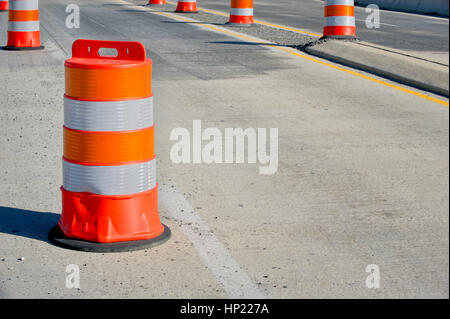 Orange and white reflective delineator posts channels traffic in order to direct traffic flow and reduce the chance of accidents on a sunny highway. Stock Photo