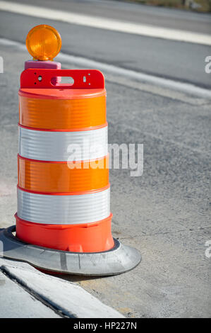 Orange barrels in highway construction zone as used in road maintenance and repair when creating traffic lane to guide drivers, summer morning side li Stock Photo