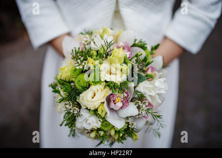 Elegant green wedding bouquet at hands of bride. Stock Photo