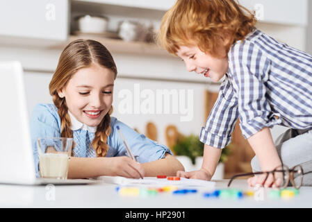 Lovely kid distracting his sister from doing homework Stock Photo