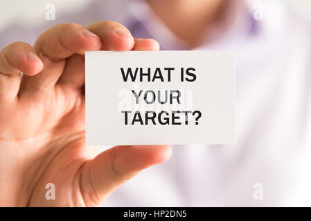 Closeup on businessman holding a card with text WHAT IS YOUR TARGET, business concept image with soft focus background Stock Photo