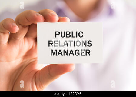 Closeup on businessman holding a card with text PUBLIC RELATIONS MANAGER, business concept image with soft focus background Stock Photo