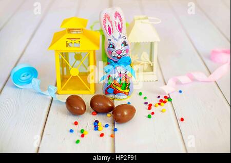 Delicious chocolate easter eggs and sweets and rabbit on wooden background Stock Photo