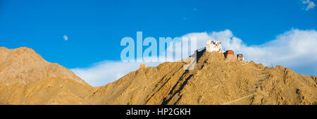 Panoramic view of Tsemo Fort and Namgyal Tsemo Gompa atop a mountain with moon rising in Leh, Ladakh, India Stock Photo