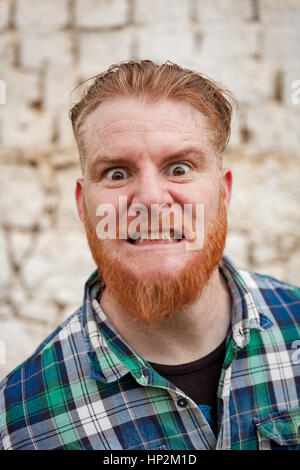 Portrait of red haired hipster man with blue plaid shirt expressing a emotion Stock Photo
