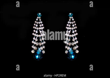 metal earrings with blue stones on a black background Stock Photo