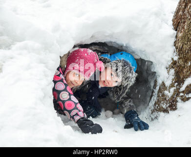 Young boy and girl hiding in a snow cave they made Stock Photo