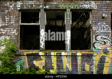 Graffiti and vandalism in abandoned derelict industrial building. Stock Photo