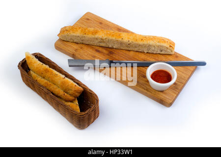 baked garlic bread cut in strips in a basket and cutting board Stock Photo