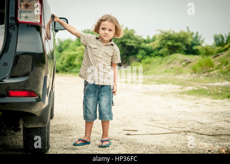 little boy standing near the car at the day time Stock Photo