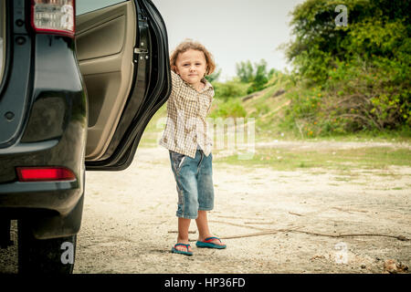 little boy standing near the car at the day time Stock Photo