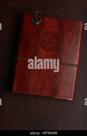 Closed book on wooden table with brown leather cover Stock Photo