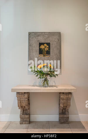 Sunflowers in vase beneath framed picture of flowers Stock Photo