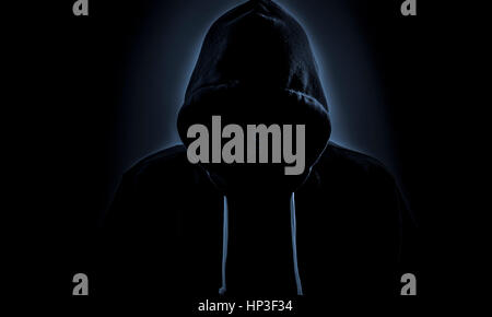 Malicious figure in hood lurking in the dark Stock Photo