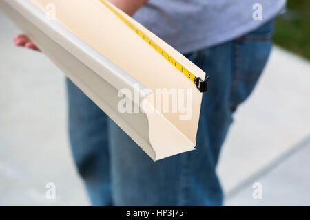 Worker Measuring An Aluminum Rain Gutter Feeding Through Seamless Shaping Machine. Stock Photo