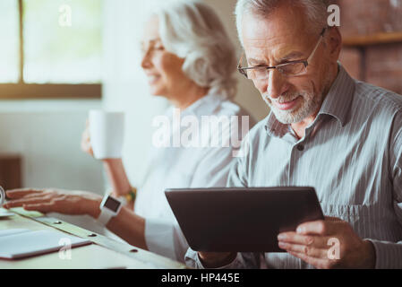Pleasant aged man using tablet Stock Photo