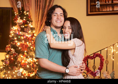 portrait of hugging couple in christmas  eve. Young man and woman portrait with christmas tree Stock Photo