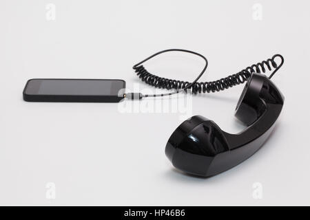 Old phone reciever and cord connection with new phone. Funny hotline concept. Stock Photo