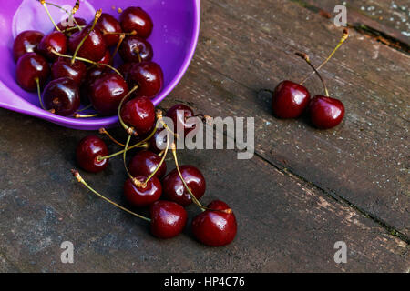 Cherries on wooden table. it poured from the plate Stock Photo