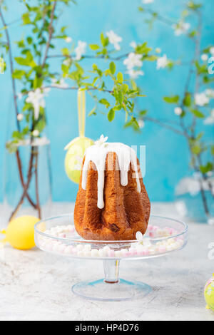 Traditional Easter cake with colored eggs and flowers. Blue background. Stock Photo