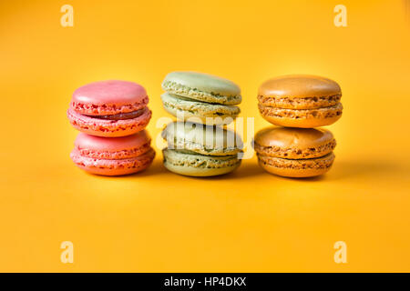 pink, orange and green macarons on yellow background Stock Photo