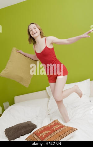 Model released , Junge Frau, 25+, springt im Bett - woman jumping in bed Stock Photo