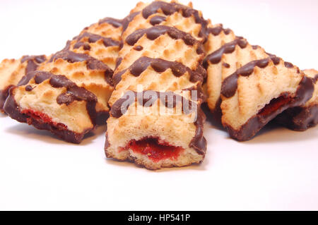 Pile of shortbread cookies with jam and chocolate icing on white background. Stock Photo