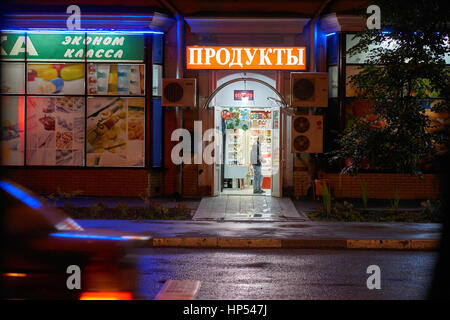 Moscow, Russia - July 21, 2015: Young man pays money in the food store at night on Eniseyskaya street. Russian text is translated as food store. Stock Photo