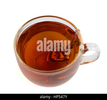 Brewing black tea in the transparent glass cup with heart shape tea strainer. Isolated on white Stock Photo