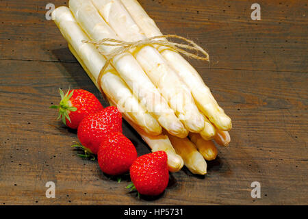 Freshly harvested asparagus and strawberries on a rustic, old wooden board Stock Photo