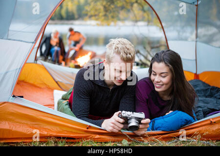 Couple Checking Pictures Into Camera While Lying In Tent Stock Photo