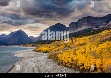 Dramatic sky in Autumn in Glacier National Park, Montana, USA. fall foliage in peak color on the shore of lake sherburne. clouds and smoke from forest Stock Photo