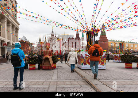 Moscow, Russia. Sunday, Feb. 19, 2017. Unidentified people on decorated Manege square. Moscow Kremlin in the background. Maslenitsa, pancake, cheese fare week festival, carnival started in the city. People enjoy street performances and eat hot pancakes. This is also farewell to winter festival. The day is warm (+2C, about 36F) but gloomy. © Alex's Pictures/Alamy Live News Stock Photo