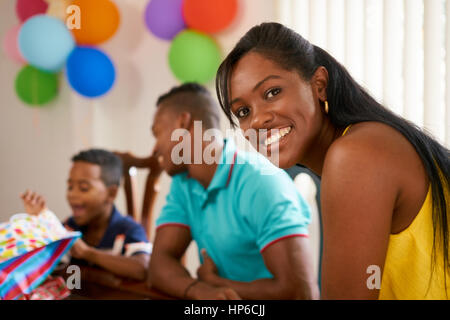 Happy black family at home. African american father, mother and child celebrating birthday, having fun at party. Portrait of young woman smiling at ca Stock Photo