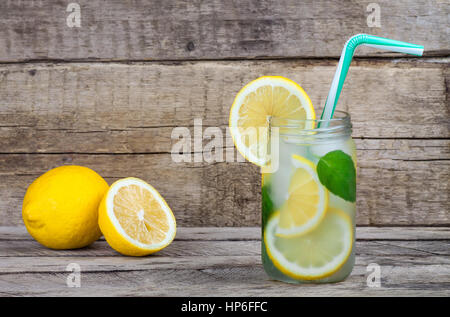 Summer fruit drink on wooden background. Cold lemonade with ice. Detox citrus infused flavored water. Refreshing summer homemade cocktail with lemon.  Stock Photo