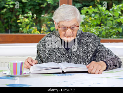 Happy elderly woman reading a book in the room Stock Photo