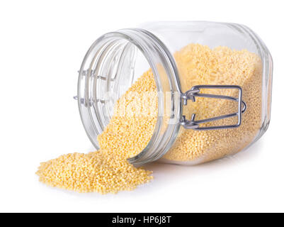 millet in a glass jar isolated on white background. Uncooked dry millet scattered out of glass transparent container Stock Photo