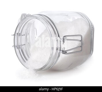 Granulated sugar in glass jar isolated on white background. Sugar scattered out of transparent container Stock Photo