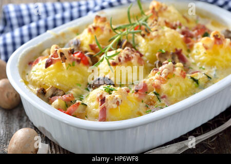 Hearty potato dumpling  gratin with Emmentaler cheese, bacon and vegetables freshly served from the oven Stock Photo